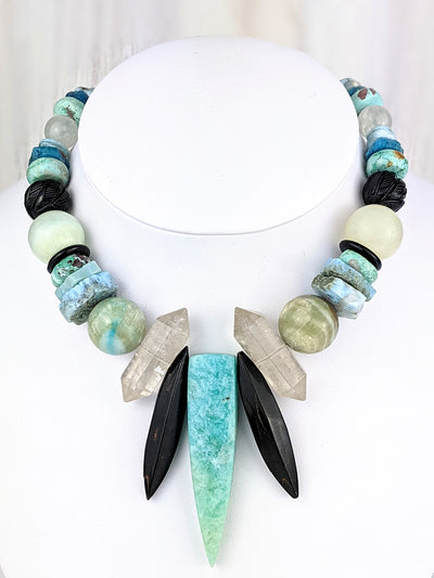Ahja is the magic that makes for a happy day. Her Russian amazonite dagger measures approximately 66mm x 16mm and is flanked by black coral spikes and double terminated rock quartz. The easy elegance of aqua tones takes a cool journey with black accents.