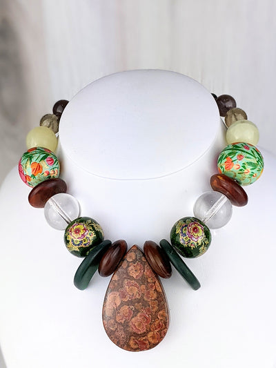 Elin shows strength and calming beauty. Sustainability is alive and well in this stunning necklace, anchored by a hefty desert rose jasper pendant. Japanese handpainted wooden beads circa 1950 take the spotlight, creating a kindred response with Bohemian crystal pools of light, green Bohemian glass claws (both circa 1920), and Nepali horn. 